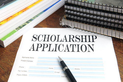 scholarship application and pen on desk surrounded by notebooks