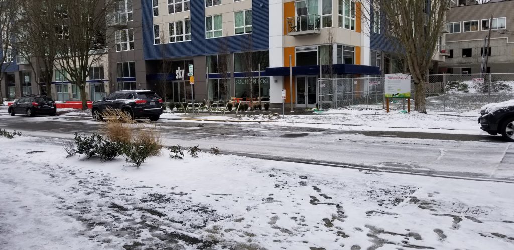 snow covered west seattle street outside apartment community